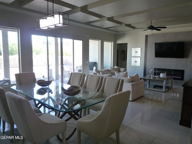 dining space featuring beamed ceiling, light tile patterned flooring, coffered ceiling, a fireplace, and ceiling fan