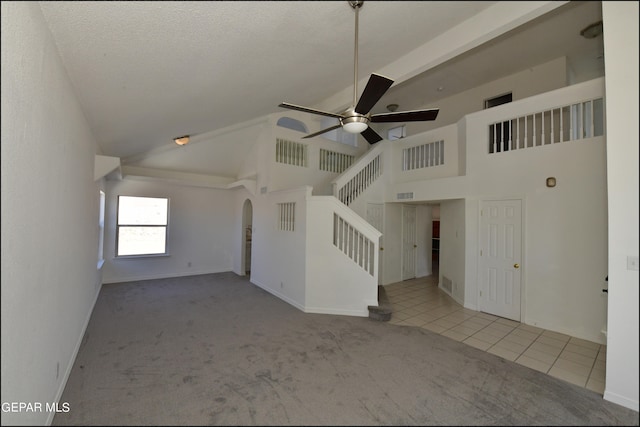 unfurnished living room featuring light carpet, a textured ceiling, high vaulted ceiling, and ceiling fan