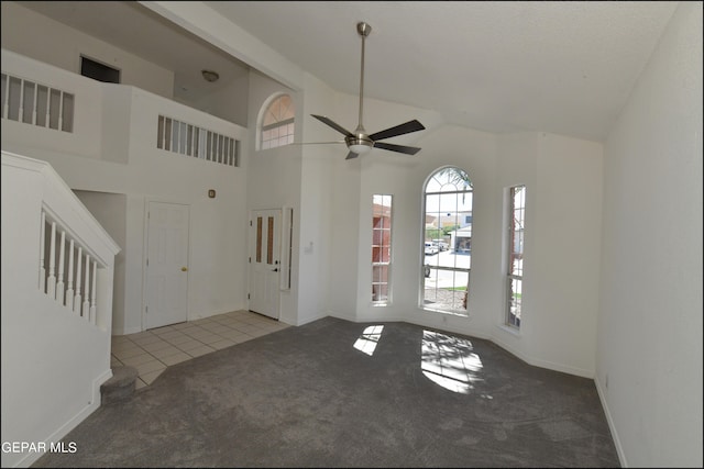 unfurnished living room featuring high vaulted ceiling, ceiling fan, and carpet flooring