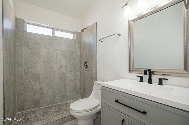 bathroom with tiled shower, vanity, and toilet