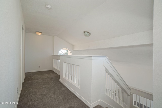 corridor featuring dark carpet and lofted ceiling