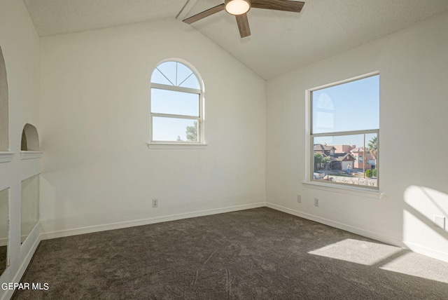 empty room with dark carpet, lofted ceiling, and ceiling fan