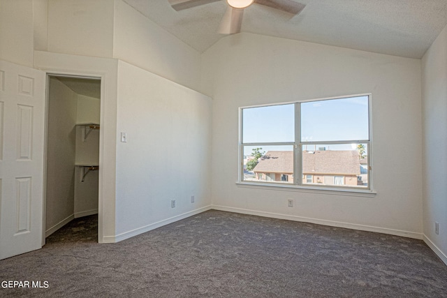 unfurnished room featuring dark carpet, vaulted ceiling, a textured ceiling, and ceiling fan