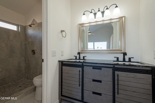 bathroom featuring a tile shower, vanity, and toilet