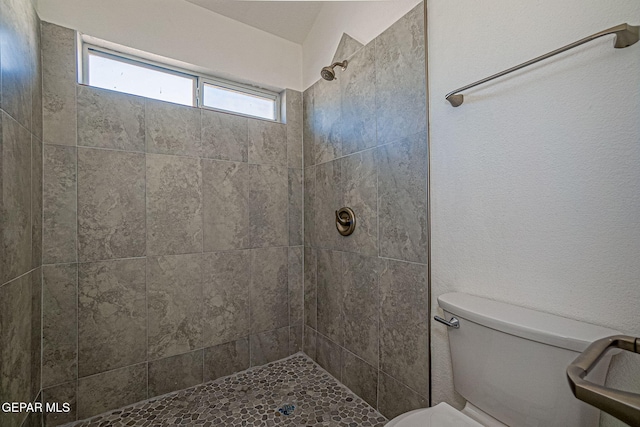 bathroom featuring a tile shower and toilet