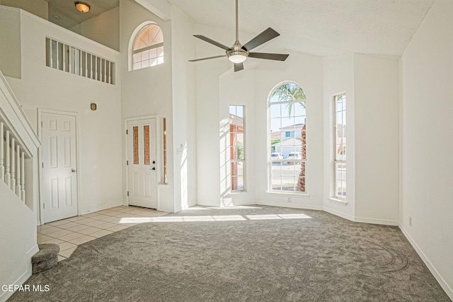 foyer entrance featuring a textured ceiling, a healthy amount of sunlight, light colored carpet, and high vaulted ceiling