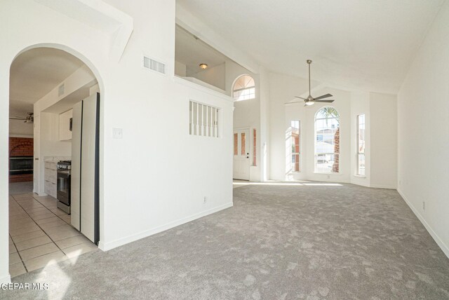 carpeted empty room featuring ceiling fan and high vaulted ceiling