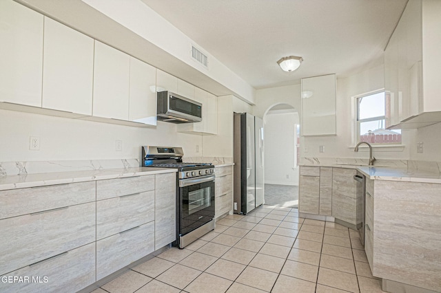 kitchen featuring appliances with stainless steel finishes, white cabinetry, and light tile patterned floors