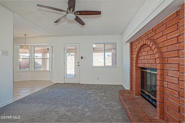 unfurnished living room featuring ceiling fan, a textured ceiling, a fireplace, and carpet flooring