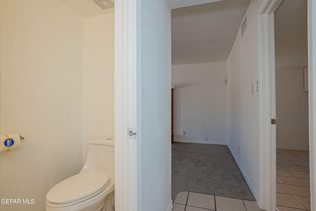 bathroom with a textured ceiling, toilet, and tile patterned floors