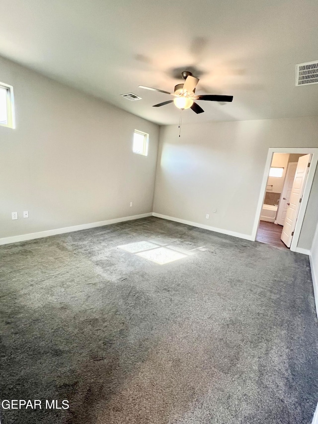 unfurnished room with ceiling fan, dark colored carpet, and a healthy amount of sunlight