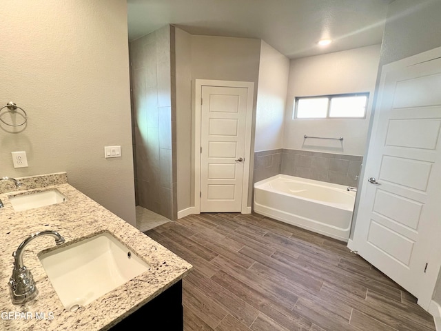 bathroom featuring wood-type flooring, vanity, and a tub to relax in