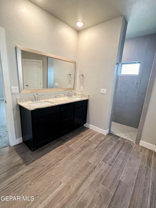 bathroom featuring a tile shower, hardwood / wood-style flooring, and vanity