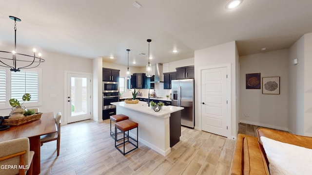 kitchen with a breakfast bar, decorative light fixtures, backsplash, a kitchen island with sink, and stainless steel appliances