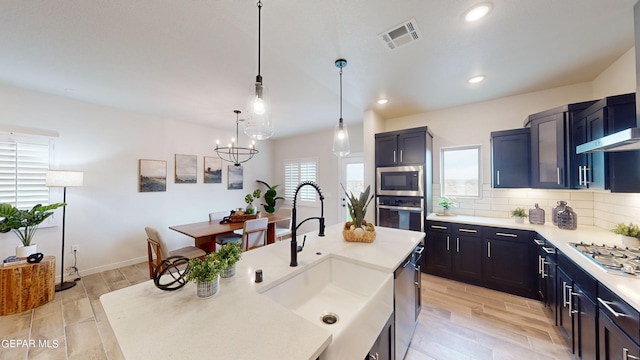 kitchen featuring sink, decorative light fixtures, light hardwood / wood-style flooring, stainless steel appliances, and backsplash