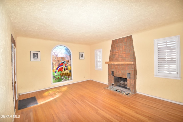 unfurnished living room with hardwood / wood-style flooring, a fireplace, and a textured ceiling