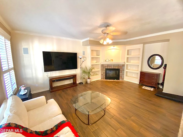 living room featuring a tiled fireplace, ornamental molding, dark wood-type flooring, and built in features