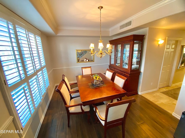 dining space with a tray ceiling, a notable chandelier, crown molding, and dark wood-type flooring