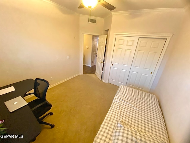 bedroom with ceiling fan, ornamental molding, carpet floors, and a closet