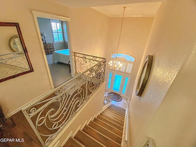 staircase featuring an inviting chandelier and crown molding