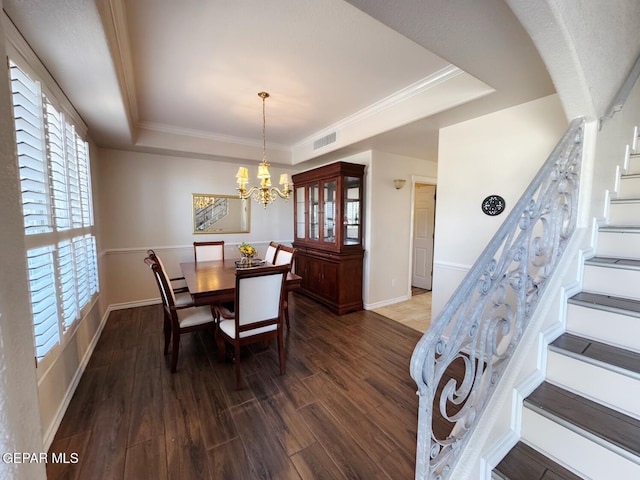 dining area featuring dark hardwood / wood-style flooring, a tray ceiling, crown molding, and an inviting chandelier