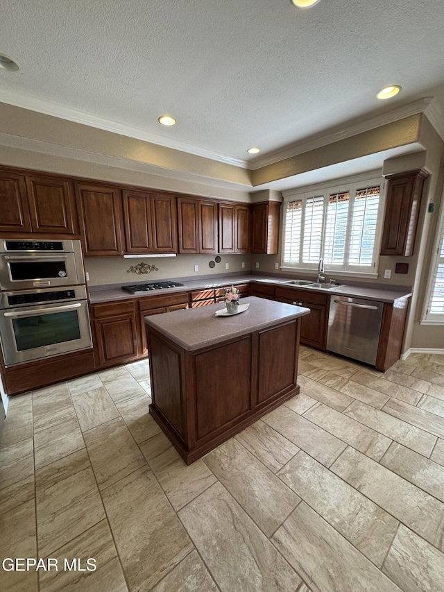 kitchen featuring appliances with stainless steel finishes, sink, a center island, crown molding, and a textured ceiling