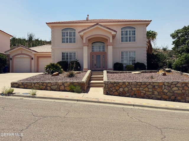6276 Los Bancos Dr, El Paso, TX 79912 - mediterranean / spanish-style home featuring french doors, driveway, an attached garage, stucco siding, and a tiled roof
