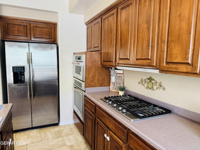 6276 Los Bancos Dr, El Paso, TX 79912 - kitchen featuring stainless steel appliances, light countertops, and brown cabinets