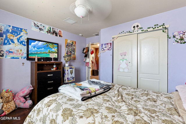 bedroom with a ceiling fan, visible vents, wood finished floors, and a closet