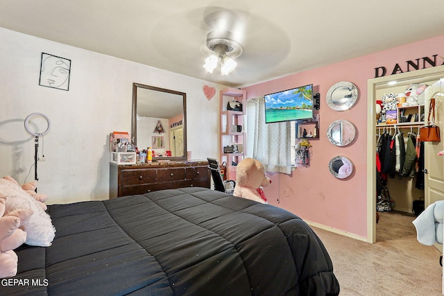 carpeted bedroom with a closet, baseboards, a walk in closet, and ceiling fan