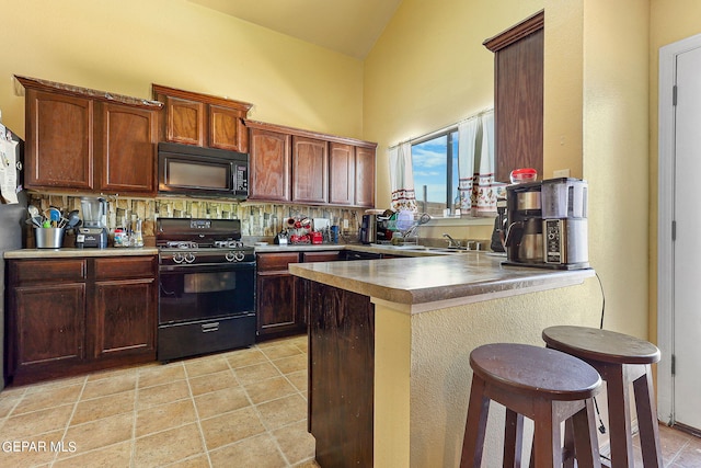 kitchen featuring a breakfast bar area, a peninsula, decorative backsplash, light tile patterned floors, and black appliances