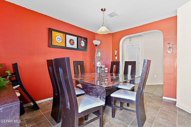 tiled dining room with arched walkways, baseboards, and visible vents