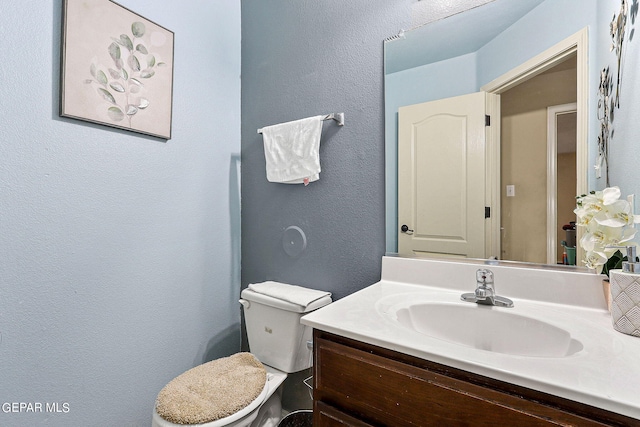 bathroom with vanity, a textured wall, and toilet