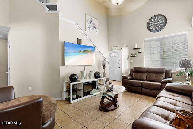living room featuring light tile patterned flooring, baseboards, and a towering ceiling