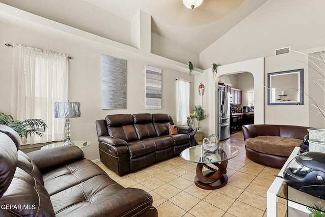 living room with arched walkways, high vaulted ceiling, light tile patterned flooring, and visible vents
