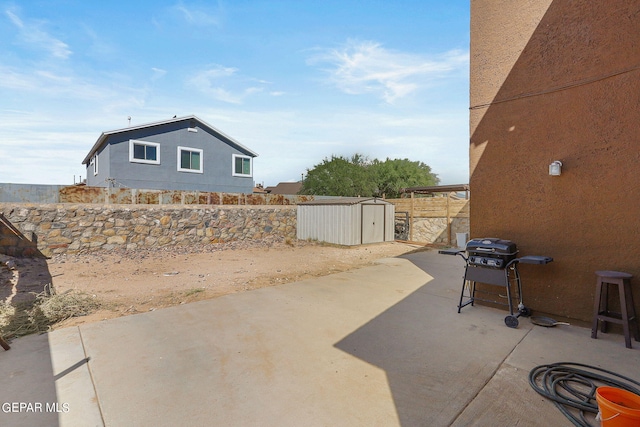 view of patio / terrace with a fenced backyard, a storage unit, an outbuilding, and grilling area
