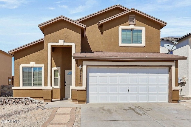 traditional-style home featuring stucco siding, an attached garage, and driveway