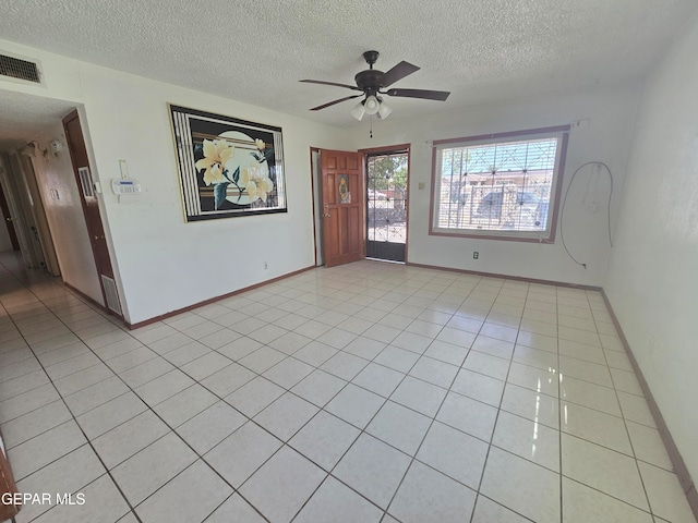 empty room with ceiling fan, a textured ceiling, and light tile patterned flooring