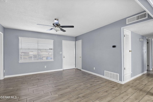 unfurnished room featuring light hardwood / wood-style flooring, ceiling fan, and a textured ceiling