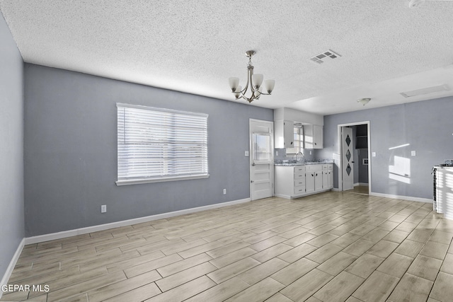 kitchen featuring a textured ceiling, light hardwood / wood-style floors, an inviting chandelier, and white cabinets