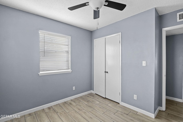 unfurnished bedroom with light hardwood / wood-style flooring, a closet, ceiling fan, and a textured ceiling