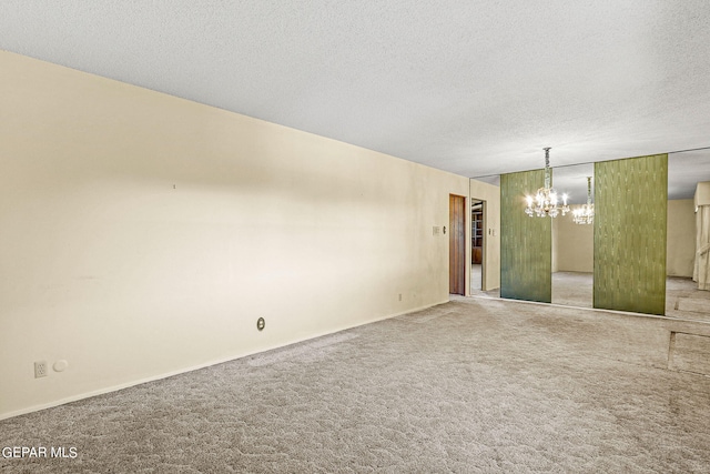 unfurnished room with carpet floors, a textured ceiling, and an inviting chandelier