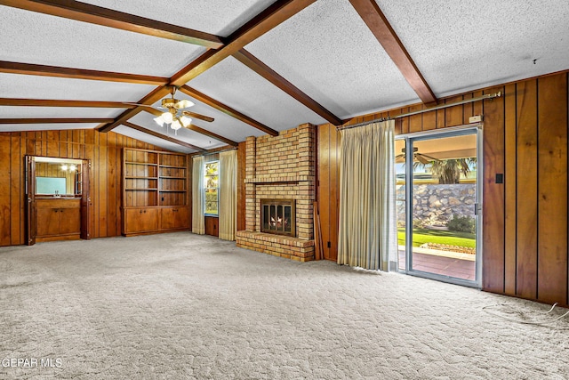 unfurnished living room with a textured ceiling, carpet floors, ceiling fan, a fireplace, and vaulted ceiling with beams