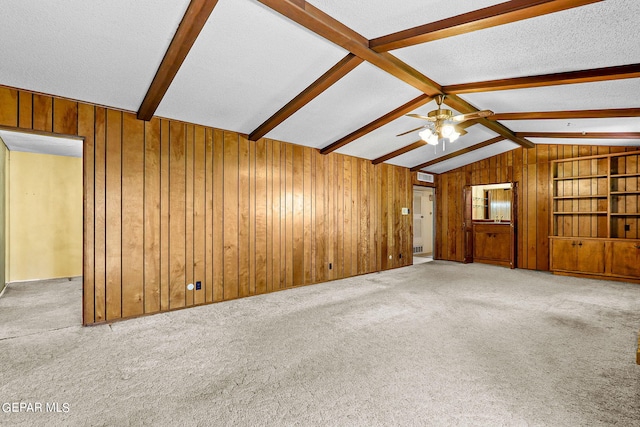 unfurnished living room featuring vaulted ceiling with beams, light carpet, ceiling fan, and a textured ceiling