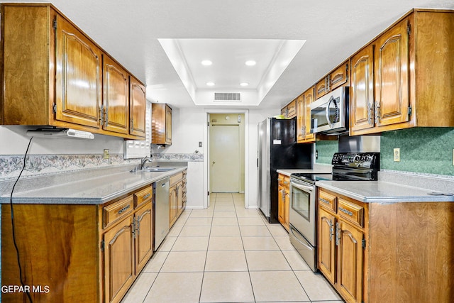 kitchen featuring light tile patterned floors, stainless steel appliances, a raised ceiling, and sink