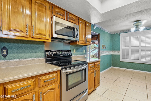 kitchen with light tile patterned floors, stainless steel appliances, and a textured ceiling