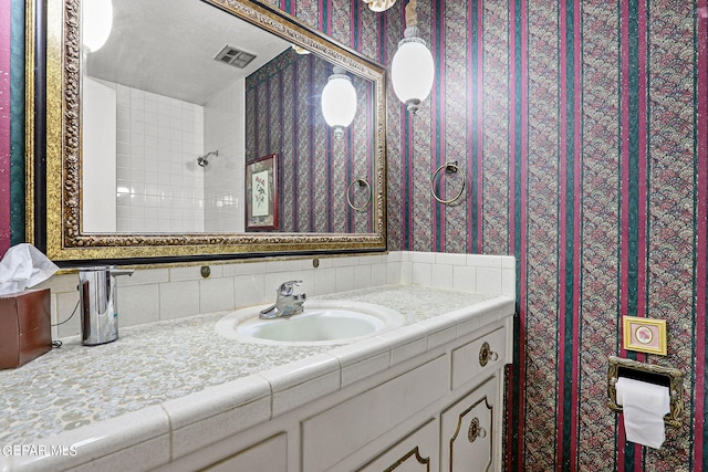 bathroom featuring a shower, vanity, and tasteful backsplash