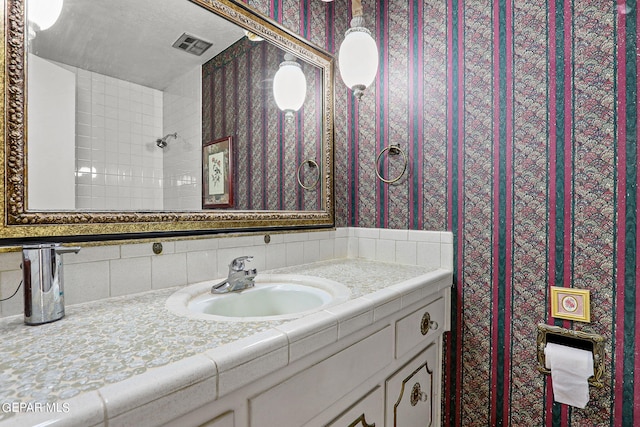 bathroom featuring a shower, vanity, and tasteful backsplash