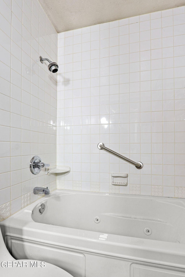 bathroom featuring a textured ceiling and tiled shower / bath