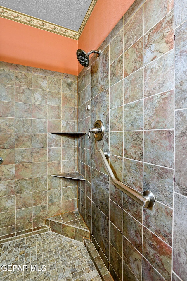 bathroom with a textured ceiling and tiled shower